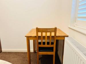 a wooden table with a wooden chair sitting at it at Budget Stay In Luton 01 R in Luton