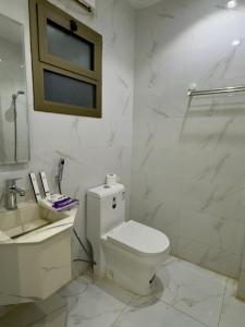 a white bathroom with a toilet and a sink at Studio with a calm and comfortable designse in Al ‘Awālī