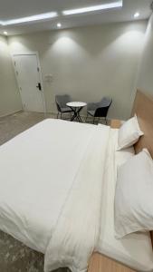 a large white bed in a room with chairs at Studio with a calm and comfortable designse in Al ‘Awālī +2 photos