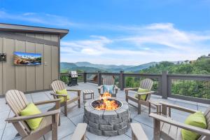 a patio with chairs and a fire pit with mountains in the background at Family Chalet With Rooftop Theater GameRoom Mins to DT in Gatlinburg