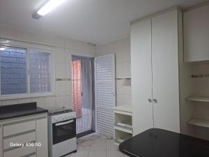 a kitchen with white cabinets and a stove top oven at Casa Guarujá in Guarujá +13 photos