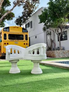 ein gelber Schulbus, der mit einer Bank im Gras geparkt ist in der Unterkunft Sunlit Hideaway plus shared Pool for 6 in Mérida