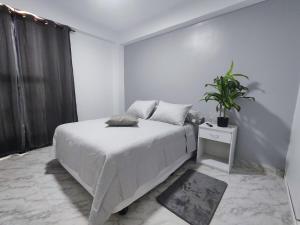 a white bedroom with a bed and a potted plant at Tus vacaciones Ideales en Costa Azul Isla de Margarita in Porlamar +19 photos