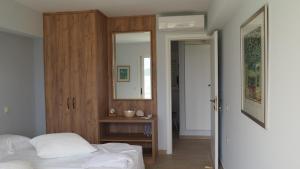 a bedroom with a bed and a wooden cabinet and a mirror at The Lakehouse in Vouliagmeni Lake