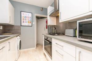 a large kitchen with white cabinets and appliances at Coal Miners Cottage - Moments To Seafront & Town in Deal +10 photos