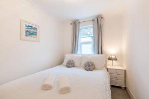 a bedroom with a white bed with a window at Coal Miners Cottage - Moments To Seafront & Town in Deal