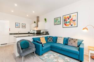 a living room with a blue couch and a kitchen at Ground Floor Garden Apartment Walpole Bay Margate in Margate