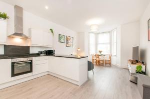 a kitchen with white cabinets and a living room at Ground Floor Garden Apartment Walpole Bay Margate in Margate