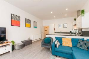 a living room with a blue couch and a kitchen at Ground Floor Garden Apartment Walpole Bay Margate in Margate