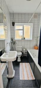 a bathroom with a sink and a toilet and a tub at Double Bed at Cozy Hailsham in London