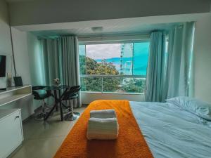 a bedroom with a bed and a large window at Loft vista panorâmica da Roda gigante e orla de BC in Balneário Camboriú