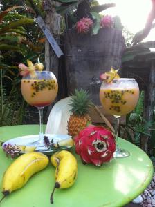 a green table with three cocktails and bananas and pineapple at Villa CACAO in Rivière-Salée