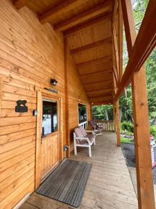 a porch of a wooden cabin with a rocking chair at The Pines Cottage on the Lake in Otter Lake