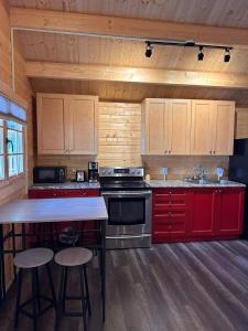a kitchen with red cabinets and a stove top oven at The Pines Cottage on the Lake in Otter Lake +10 photos