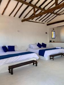 two beds in a white room with wooden ceilings at Refugio en Barichara con piscina, jardines y atardeceres únicos in Barichara +21 photos