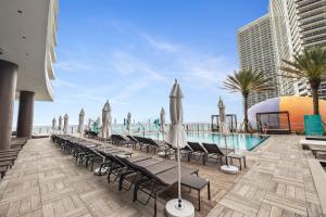 a pool with chaise lounge chairs and umbrellas at LYFE Resort Ocean View Penthouse in Hollywood