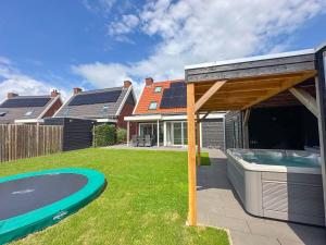 Un patio trasero con piscina y una casa. en Coast and Calm 57, en Colijnsplaat