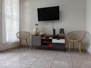 a living room with two chairs and a tv on a wall at CasaRomeroSV Casa completa 5 min de mall seguridad 3 cuart Lavad Sec aire ac 1pq in Mexicanos