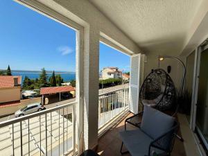 a balcony with a chair and a view of the ocean at Apartment in Dramalj 54763 in Dramalj