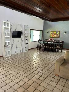 a living room with a table and a tv at Chácara paraíso da Suzy in Recife