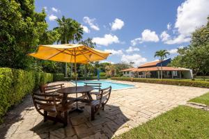 a table and chairs with an umbrella next to a pool at Chácara paraíso da Suzy in Recife