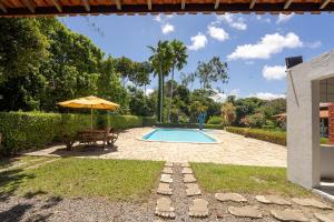 a swimming pool with a table and an umbrella at Chácara paraíso da Suzy in Recife