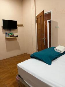 Zimmer mit einem Bett, einem TV und einer Tür in der Unterkunft Sapo Rumbia Homestay in Berastagi + 19 Fotos