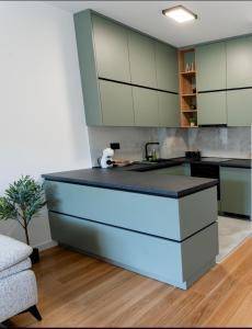 Apartman VISTA FIUME في تريبينيي: مطبخ بدولاب بيضاء وجزيرة زرقاء