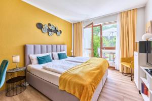 a bedroom with a large bed with a yellow wall at Besilima Apartments Deidesheim - zentral & ruhig am Kurpark in Deidesheim