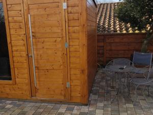 eine Holzwand mit einem Tisch und Stühlen neben einer Terrasse in der Unterkunft Échappée Relaxante en Famille près du Lac de Madine - FR-1-585-94 in Richecourt