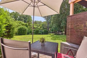 a table with an umbrella on a patio at Besilima Apartments Deidesheim - zentral & ruhig am Kurpark in Deidesheim