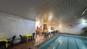 a swimming pool with chairs and tables and a restaurant at Hotel Jardim Goiás in Rio Verde