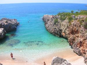 a beach with people in the water and rocks at iCampJal Beach Camp and Bar in Jal