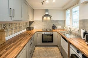a kitchen with white cabinets and a wooden counter top at 4BD Townhouse - Paddington! in London