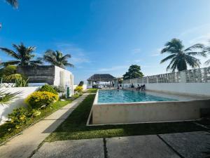 ein Schwimmbad vor einem Gebäude mit Palmen in der Unterkunft Hotel "CASA MANGATA" in Puerto Arista
