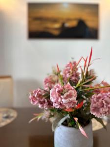 a white vase filled with pink flowers on a table at Casarão para 16 pessoas in Rio de Janeiro