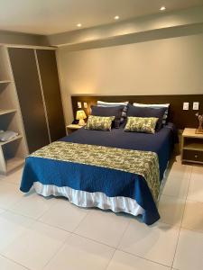 a bedroom with a large bed with blue sheets and pillows at Brisas Tropical Flat in Conde +24 photos