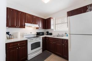 Una cocina con gabinetes de madera y un refrigerador blanco. en The Havana Haven 2br Near Brickell In Miami, en Miami