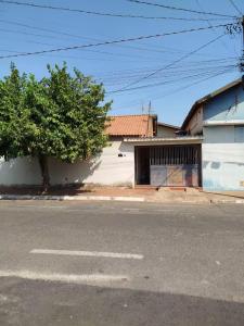 a white building with a tree next to a street at Casa Completa para Festa do Peão de Barretos in Barretos