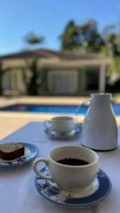 a cup of coffee and a piece of cake on a table at Quarto-Suíte Serra Petrópolis in Petrópolis