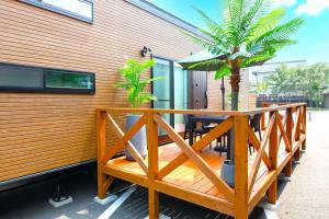 阿苏市ホテルトレーラーシップガーデン阿蘇的木甲板,配有桌子和棕榈树