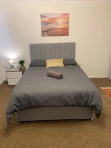 a bedroom with a large bed with a gray headboard at Cosy Rooms in London +6 photos