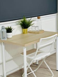 a wooden table with a chair and plants on it at Cosy Rooms in London