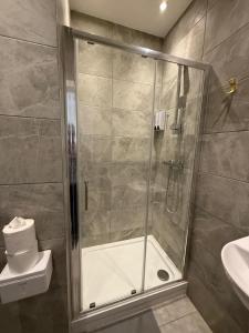 a bathroom with a shower with a toilet and a sink at Cosy Rooms in London