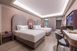a hotel room with two beds and a desk at Mercure Jingjiang Downtown in Jingjiang