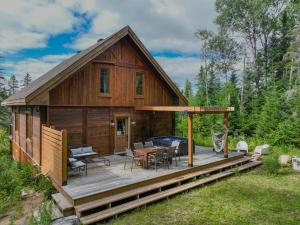 une cabane en bois avec une terrasse équipée d'une table et de chaises dans l'établissement Sara Chalet With Spa Hiking Trails, à Notre-Dame-de-la-Merci