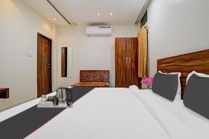 a bedroom with a large white bed and a chair at FabHotel Adiyogi Aura in Indore