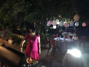 a woman in a pink dress standing in front of a table at Mer Bleue Homestay Phòng Family in Ke Ga