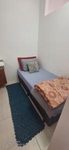 a bed sitting in a room with a blue rug at Quarto individual in Mogi das Cruzes