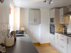a kitchen with white cabinets and a black counter top at Gable Cottage in Keswick